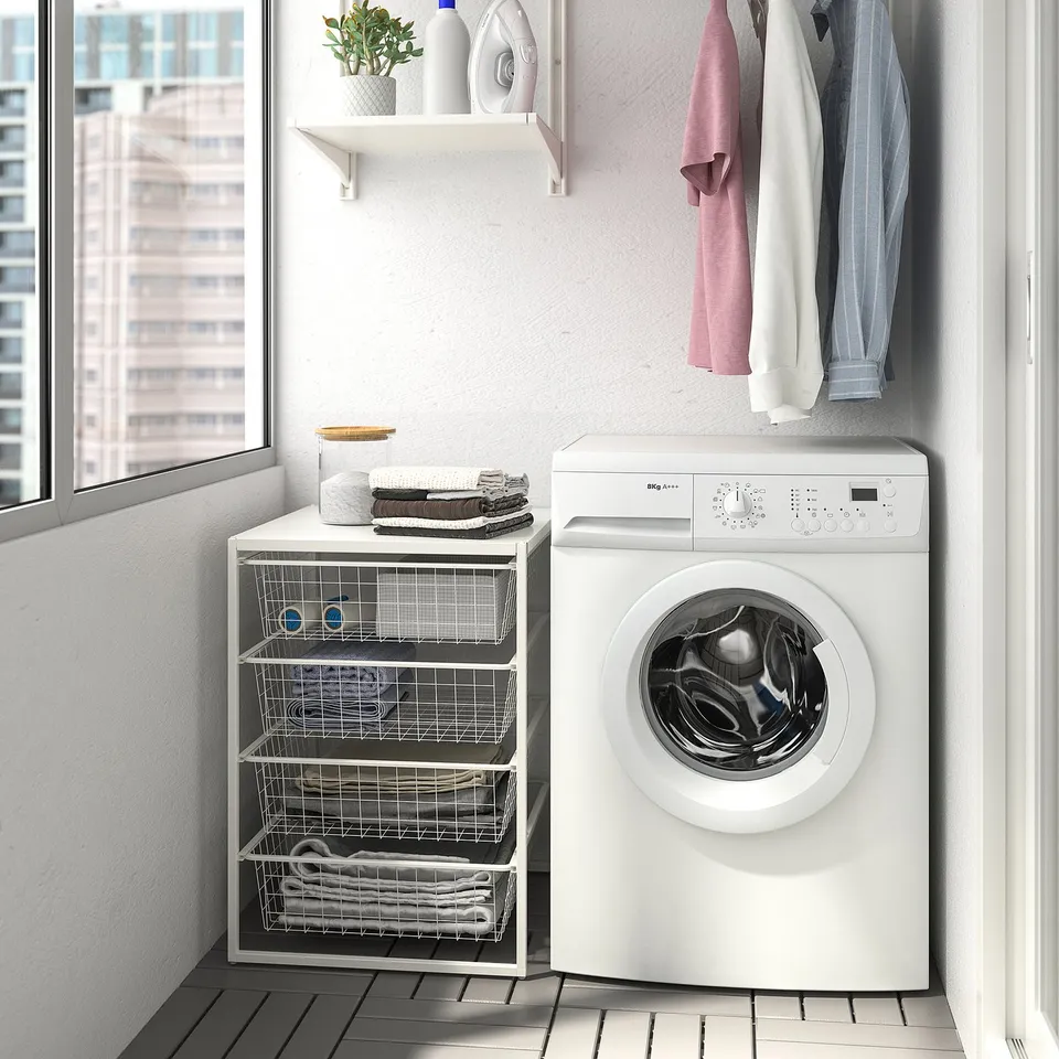 White JONAXEL storage next to washing machine with shelves and baskets.