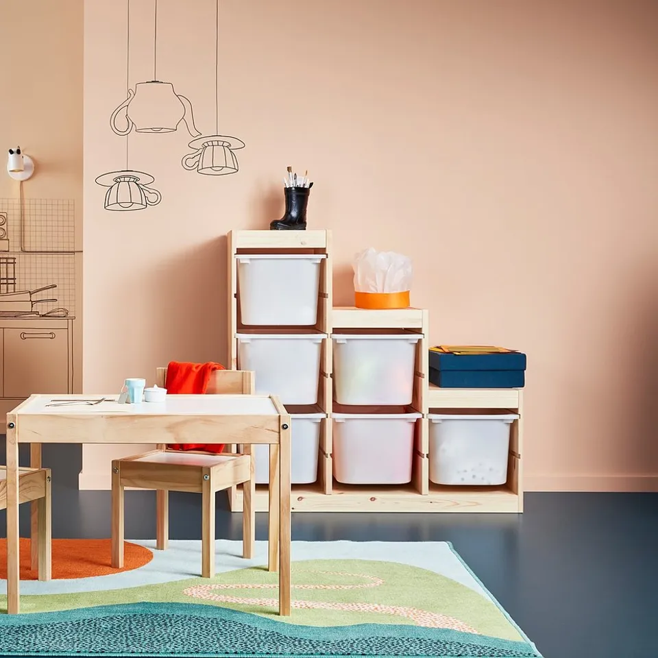 Colourful kids play area with white LÄTT table and chairs, storage boxes, toy kitchen, and wall decorations.