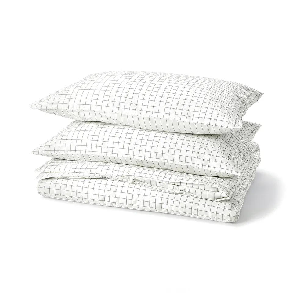 A stack of white DOFTAKLEJA bed linens in grid pattern, folded neatly.