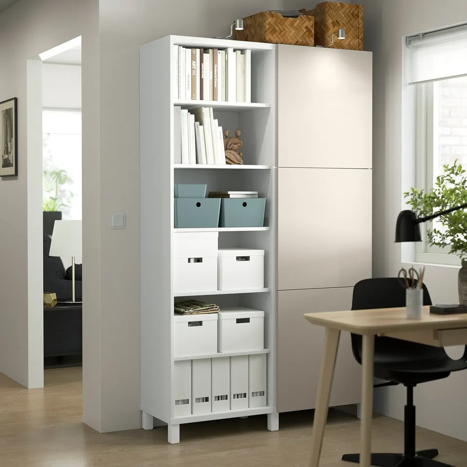 White BESTÅ storage unit, adjustable shelves, corner fit. Top: closed door, bottom: open shelves with boxes, books, decor.
