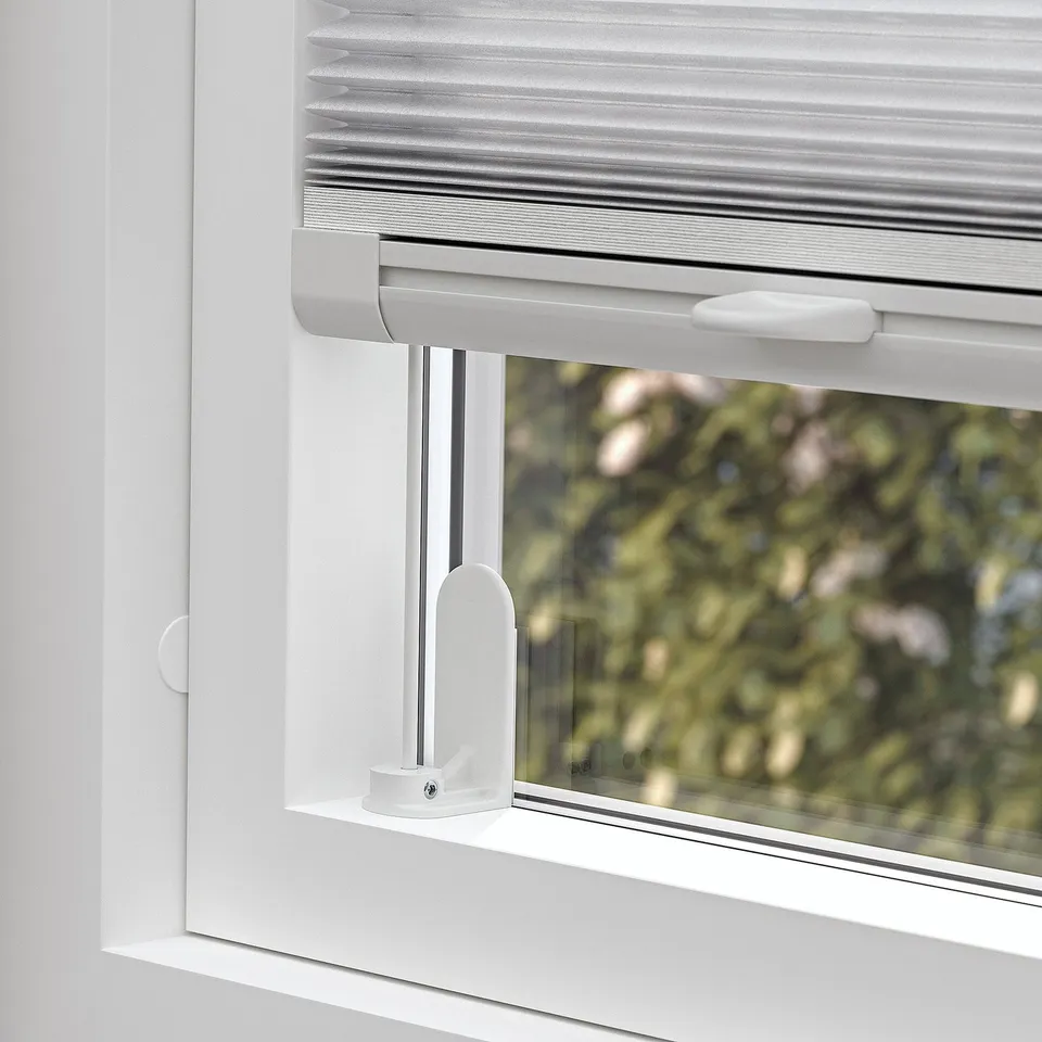 Window with pleated blind partially open, controlled by top handle, offering light filtering and privacy.