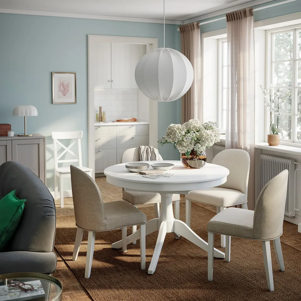 Dining room with ROSENTORP table, chairs, and floral centrepiece. Light blue walls and sheer curtains create inviting space.