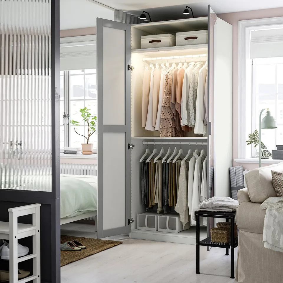 Modern wardrobe with mirror door showing organised clothes, shelves, and lights. Interior storage visible.