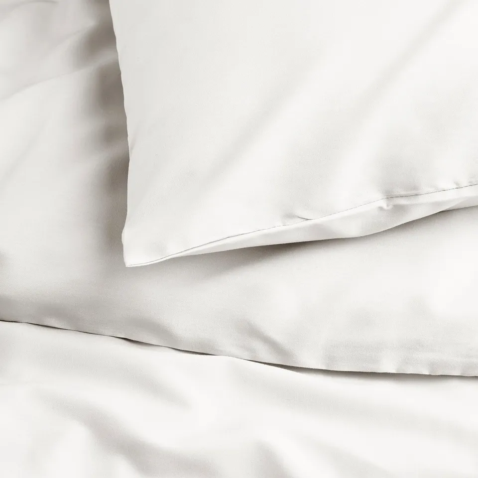 Neatly arranged white bed sheet and pillowcase set. Crisp, smooth fabric with no visible wrinkles.
