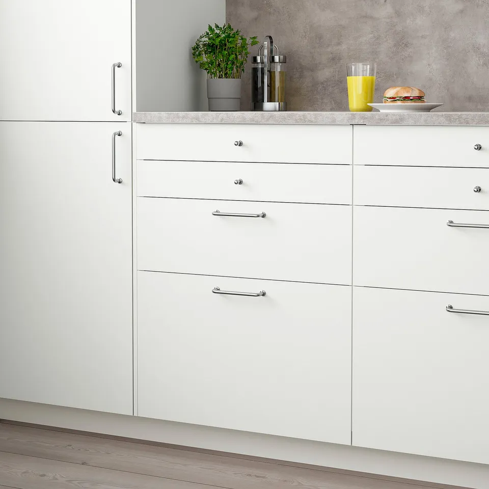 White VALLSTENA kitchen cabinet with drawers and silver handles, minimalist design.