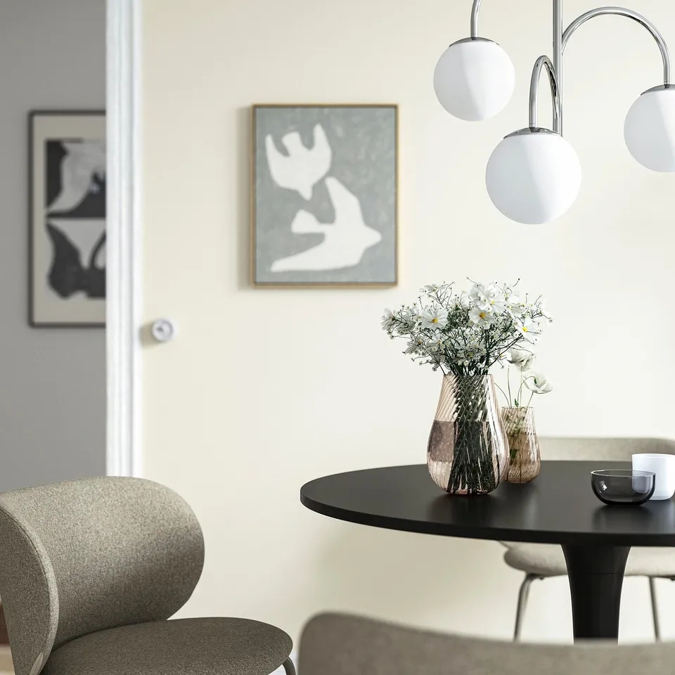 Modern dining area with vase, flowers, and light fixture.