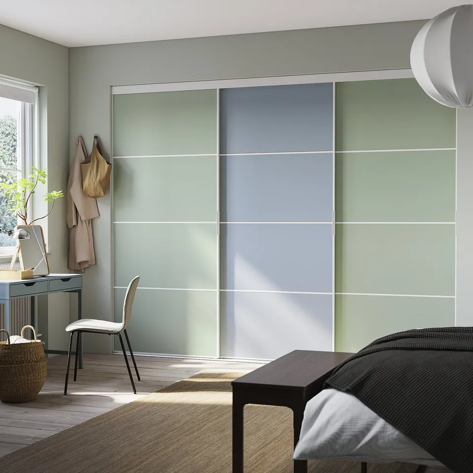Modern bedroom with light green sliding closet doors, a white chair, and a wooden floor.
