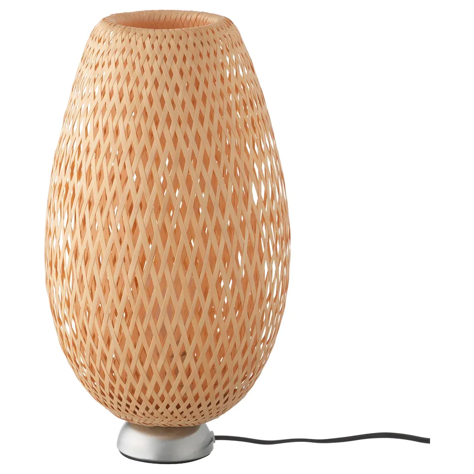 A BÖJA lamp with a woven bamboo shade and a metal base, casting intricate light patterns.