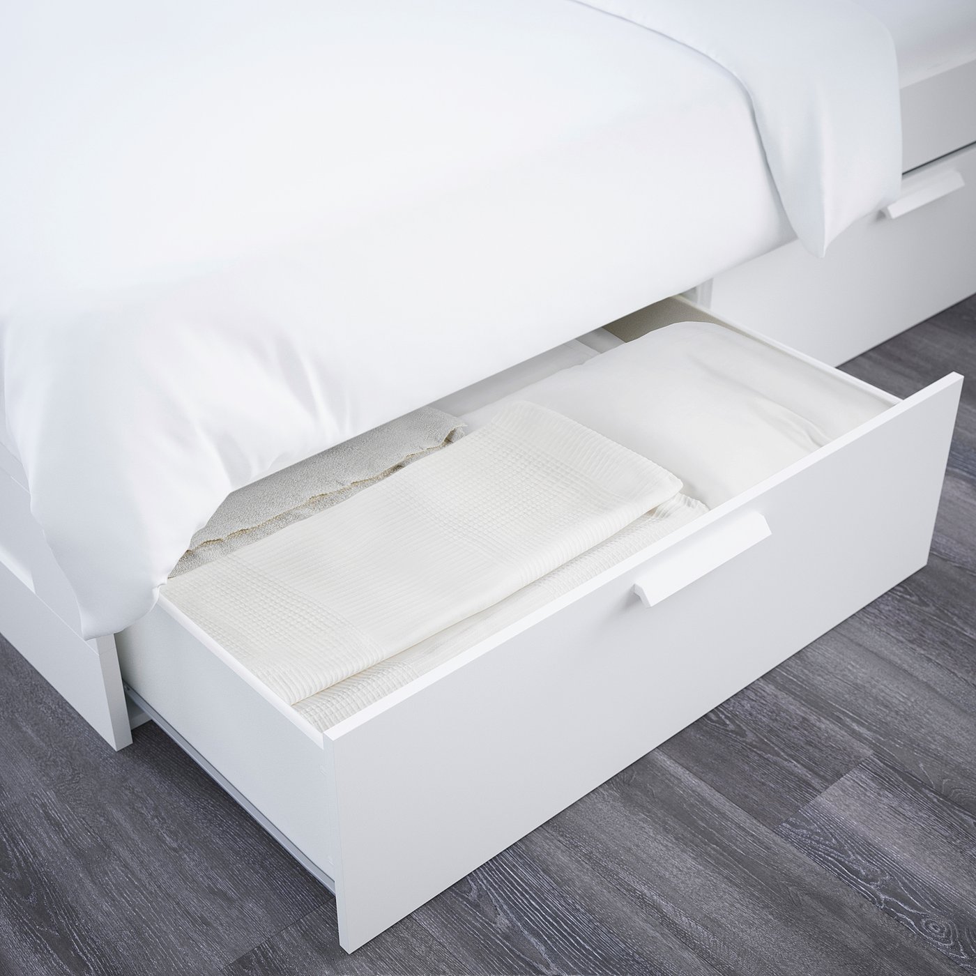 Open white bed frame with four visible drawers underneath, suggesting storage space.