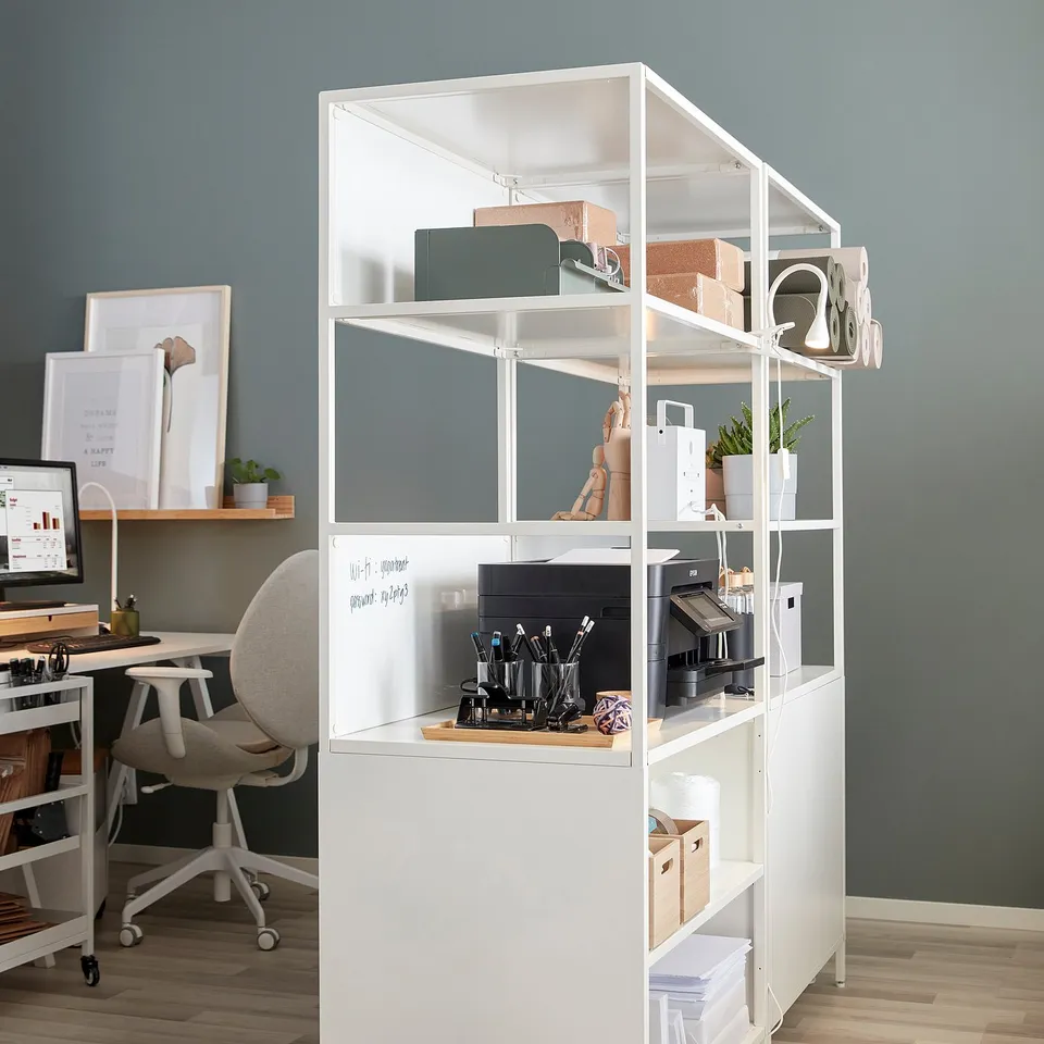White trotti office cabinet with open & closed storage, printer, stationery, plants, and dividers for privacy.