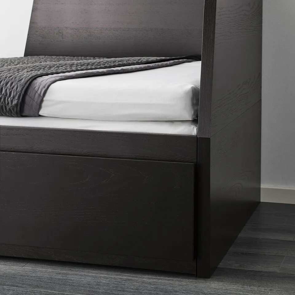 Black daybed with white and grey bedding, showcasing its dual functionality as a sofa and bed.