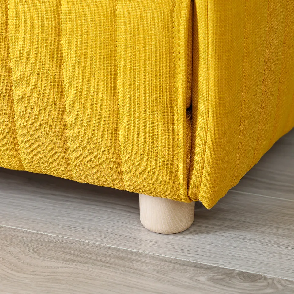 Mustard yellow sofa bed detail, showcasing sleek wooden leg and quality fabric.