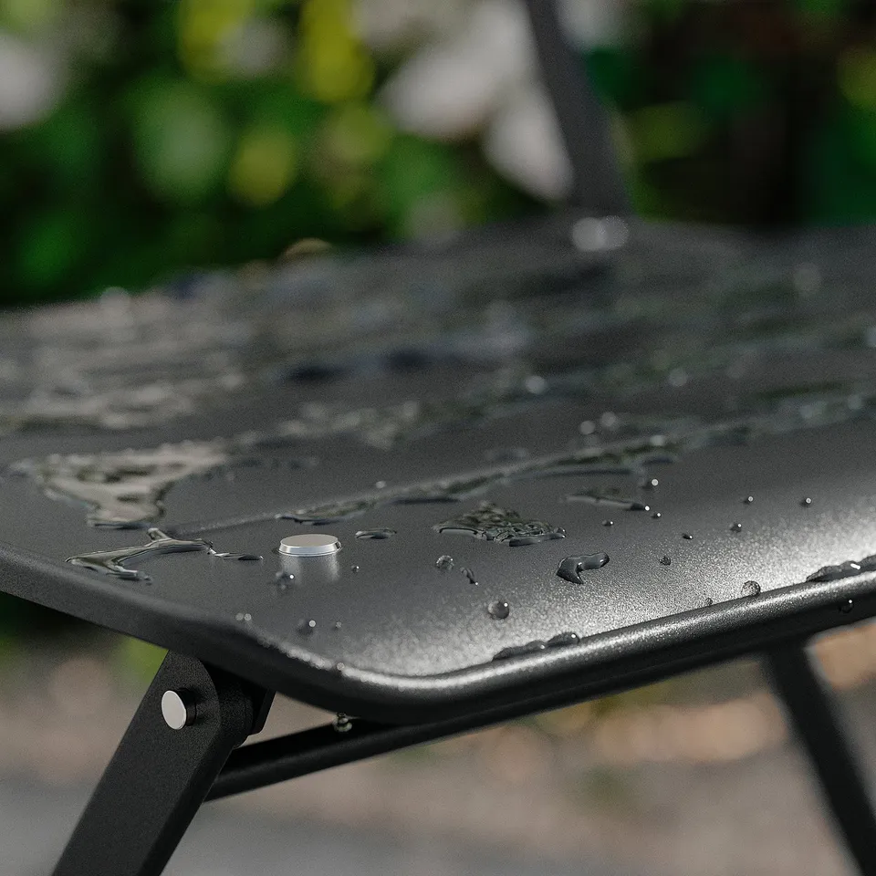 Black metal garden table with water drops, wet surface, outdoor scene.