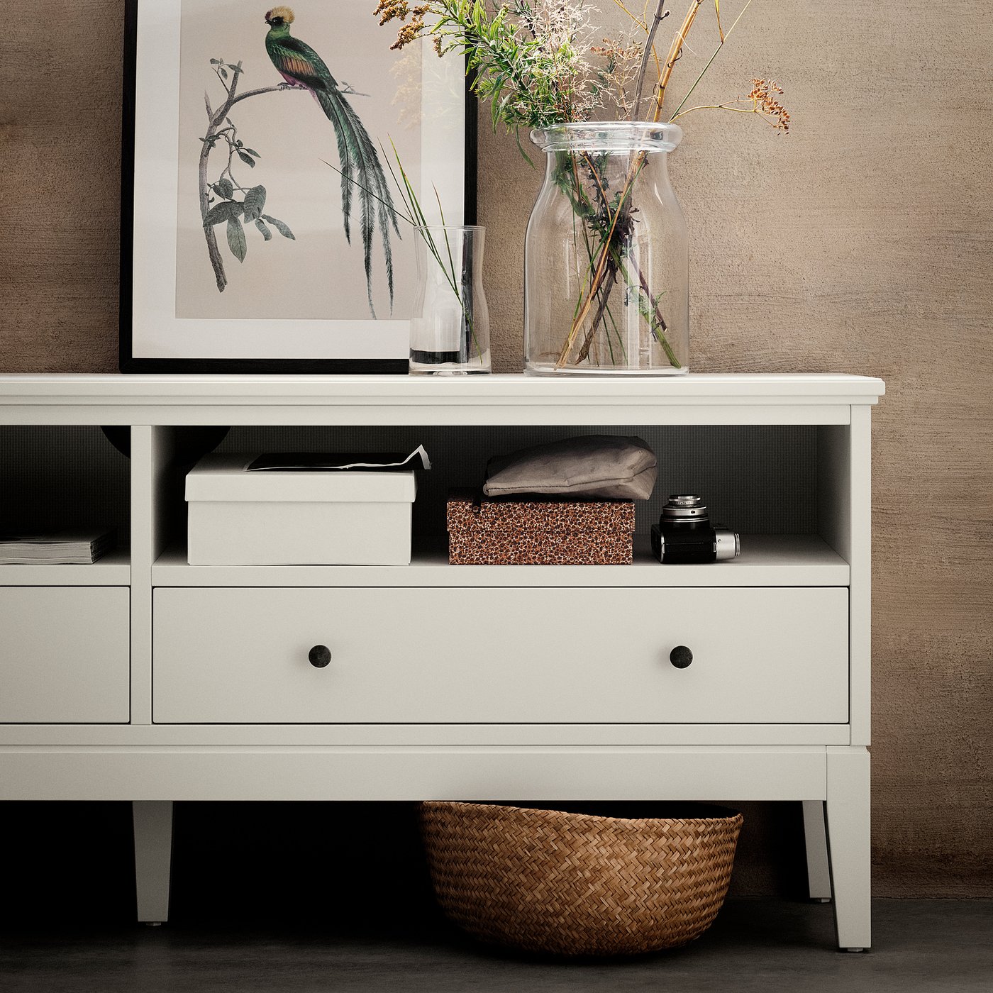 White IDANÄS tv stand with drawers, holding framed art, vases with dried plants, and storage boxes.