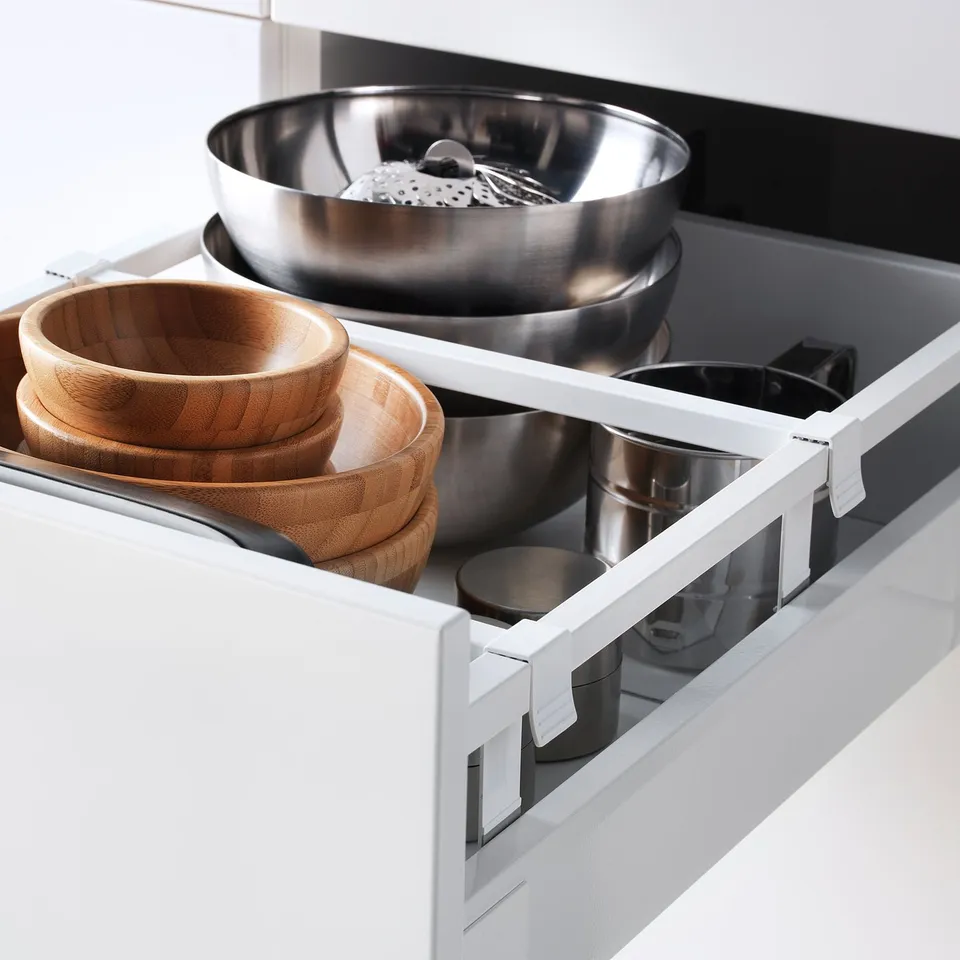 Open kitchen drawer showing wooden and metal bowls, organised with adjustable dividers.