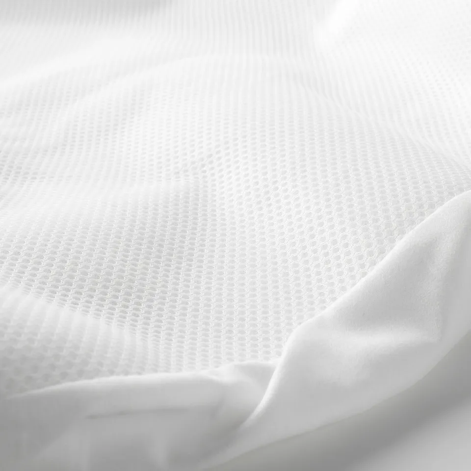 Close-up of a white, textured mattress protector, showcasing its soft, breathable fabric.