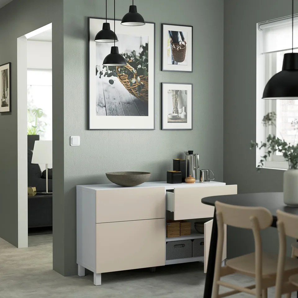 A modern kitchen with a BESTÅ sideboard featuring adjustable shelves, drawers, and push-open functionality, with black pendant lights hanging above.