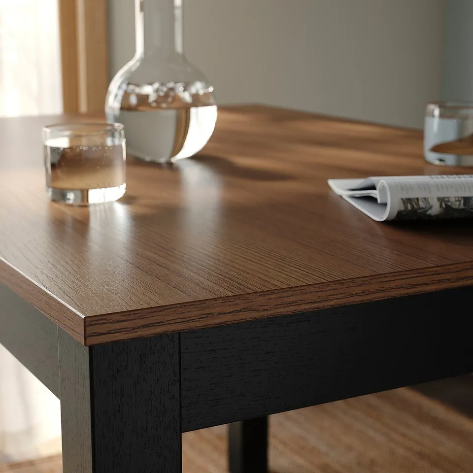 Wooden table with smooth, varnished surface. Decorative items placed on it. Table edge close-up highlights quality finish.