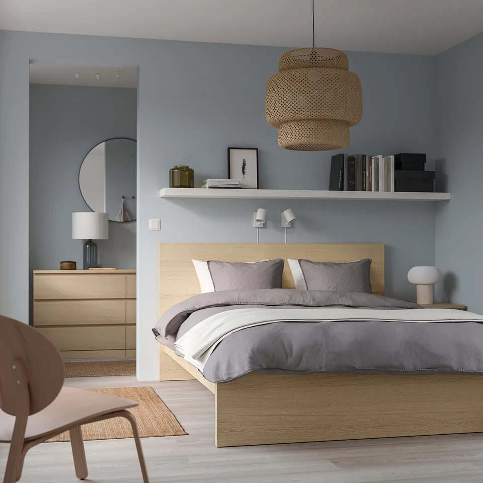 Modern bedroom with MALM bed, grey bedding, pendant & wall lights, dresser, round mirror, blue walls, light wood floor.