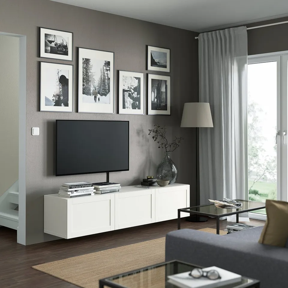 Modern living room with BESTÅ tv bench, flat-screen tv, photos, vase, books, grey sofa, coffee table, lamp, wide storage.