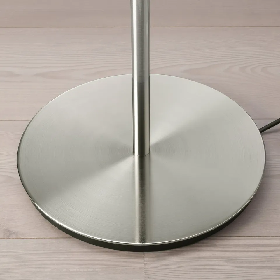 Silver metallic lamp base, sleek and modern, shown on wooden surface. Polished steel finish reflects light, appears sturdy and well-crafted.