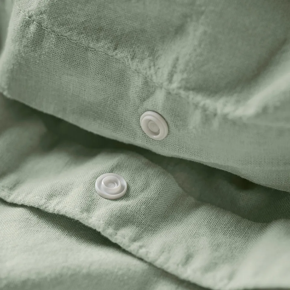 Close-up of light green duvet cover featuring two white snap fasteners.