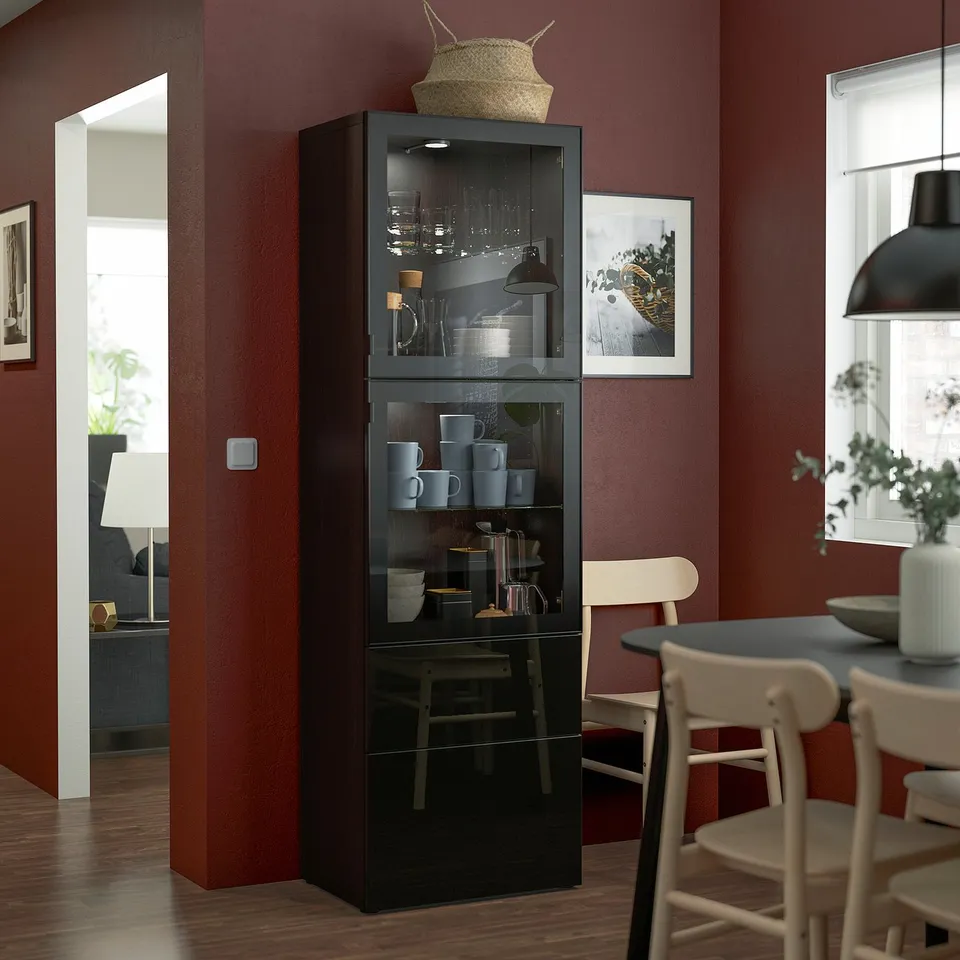Black BESTÅ cabinet in dining room with items. Nearby chair and table.