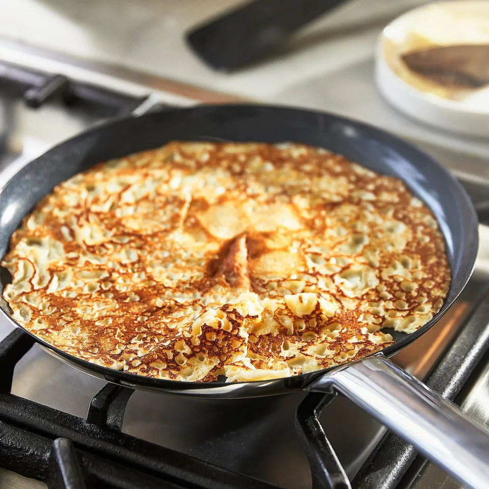 Non-stick pan on stove cooking pancakes, showcasing even heat distribution and easy flipping design.
