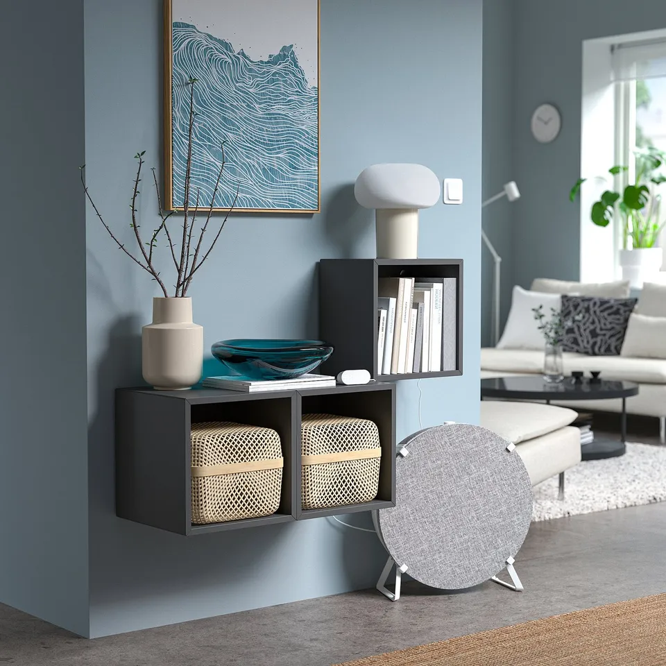 Blue living room with dark shelf, lamp, air monitor, and artwork.