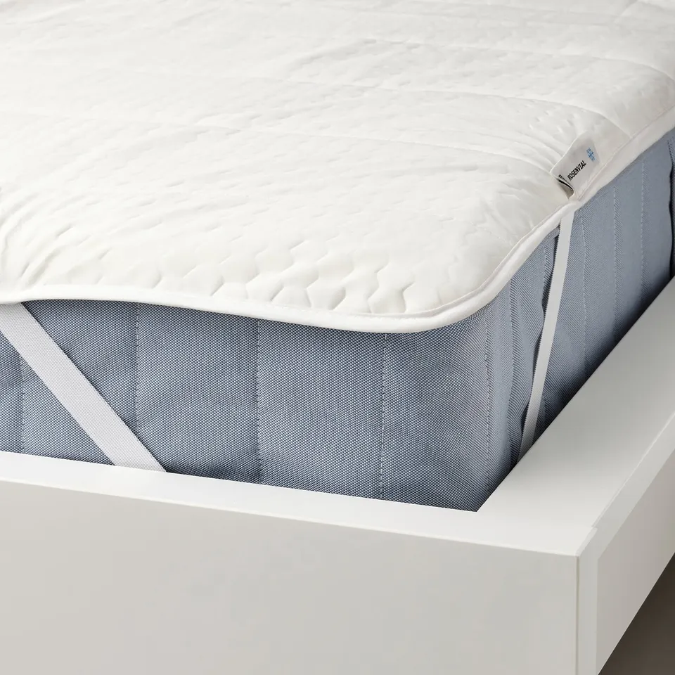 White mattress protector with elastic corners on grey-blue mattress, designed to regulate temperature and protect.