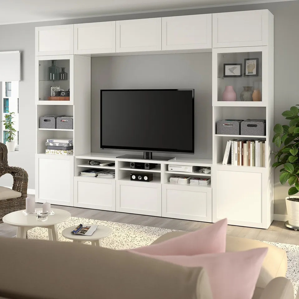 Modern living room with large white BESTÅ entertainment unit, tv, books, & plants; sleek & spacious.