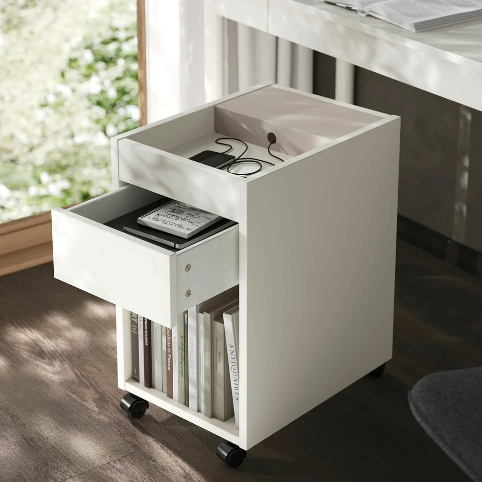 White TONSTAD mobile drawer unit with open compartment revealing small items and books, on wheels.