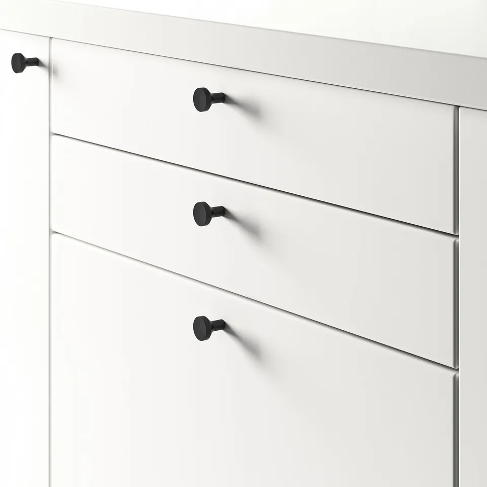 Close-up of white drawer unit with four black BAGGANÄS knobs, suitable for 16-21 mm thick doors.