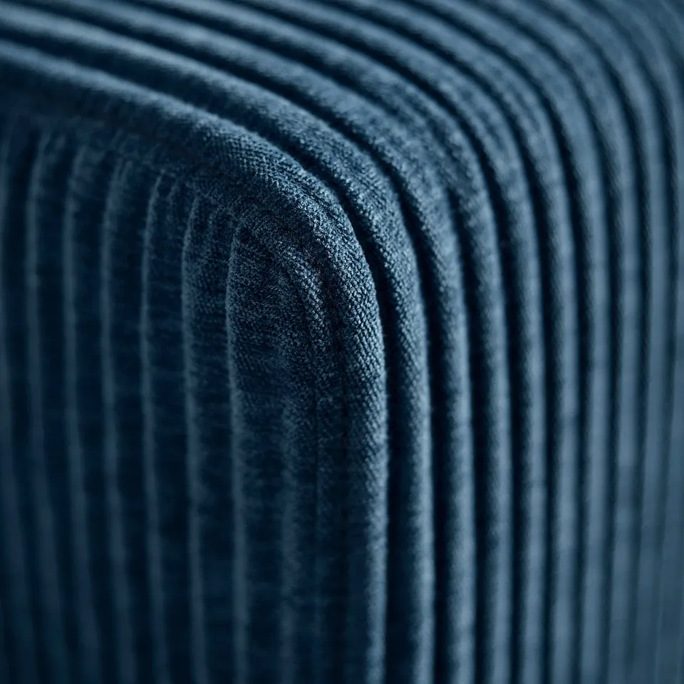 Close-up of soft, textured, dark blue fabric sofa, showcasing its high-quality, comfortable material and precise stitching.