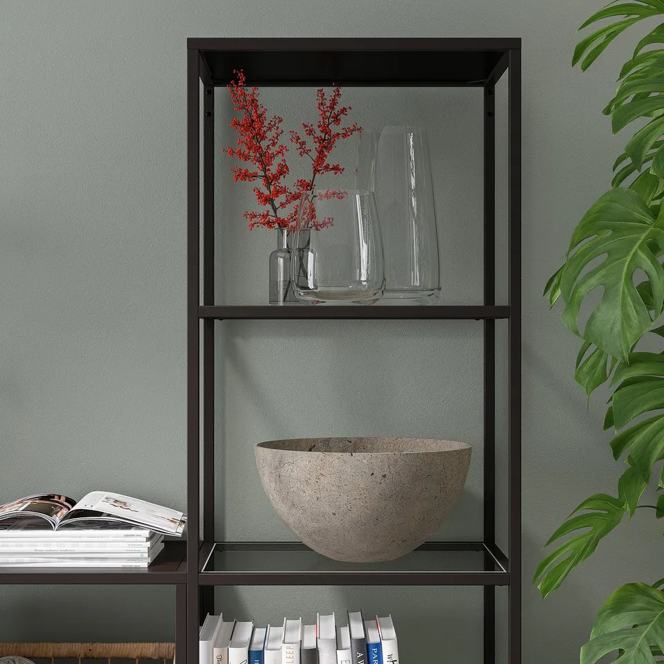 Shelf with glass tiers; holds books, vases, and bowl. Adjustable feet for stability.