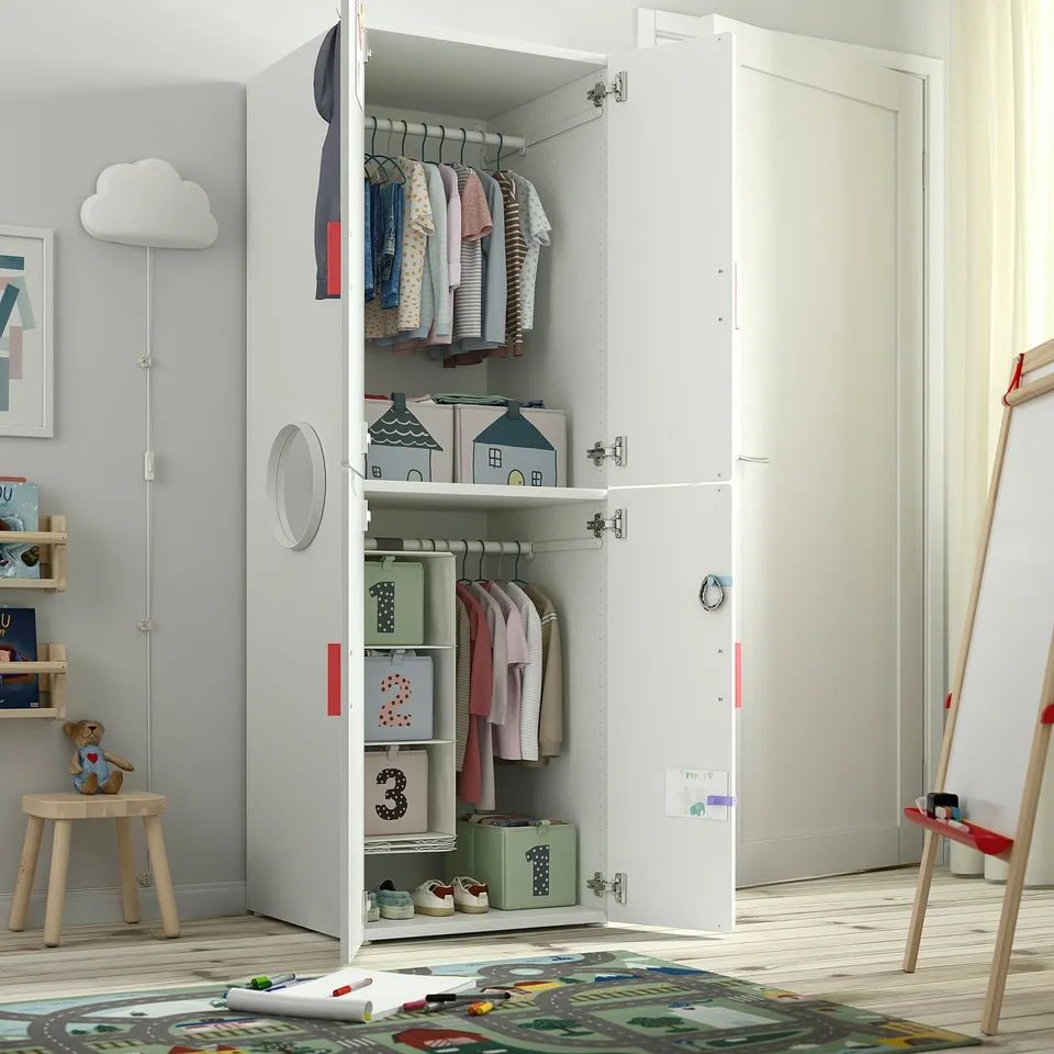 Open wardrobe with clothes hangers and boxes. Kids room storage with colourful containers.