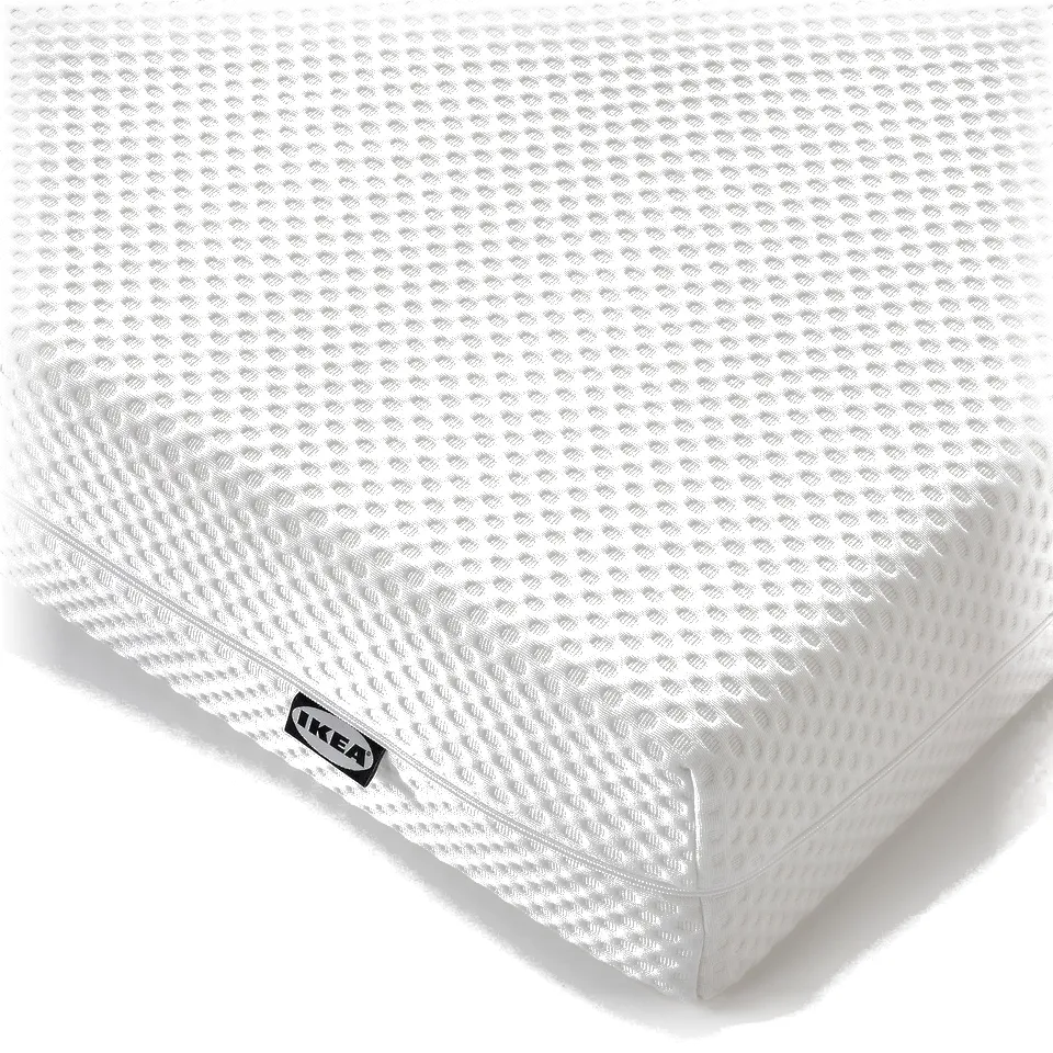 Close-up of IKEAs ÅBYGDA mattress, showcasing its firm, textured white surface with a subtle pattern, and a visible brand tag.