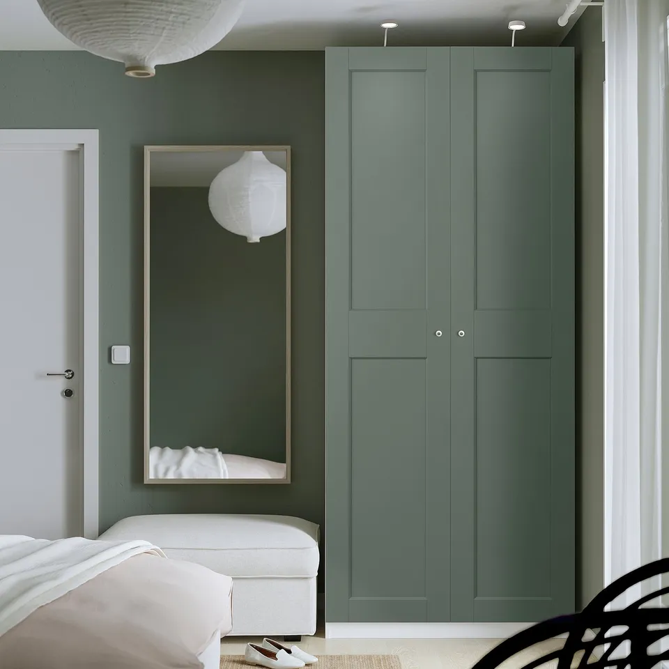 Modern bedroom with tall green PAX wardrobe and large mirror, white bed, and sleek design.