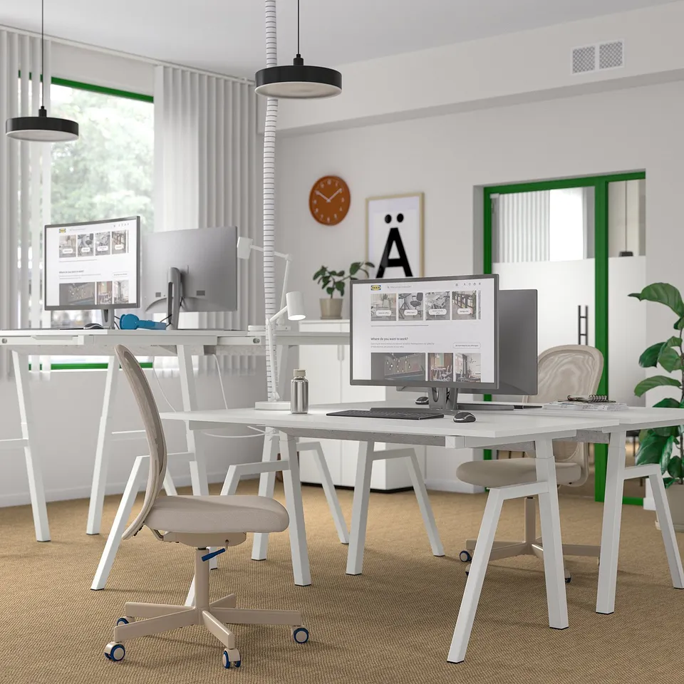 Modern office with two TROTTEN sit/stand desks, computers, and minimal decor.