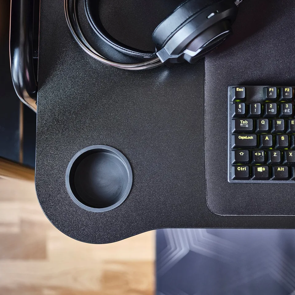 Black gaming desk with headphone and cup holders. Keyboard on stable steel surface.