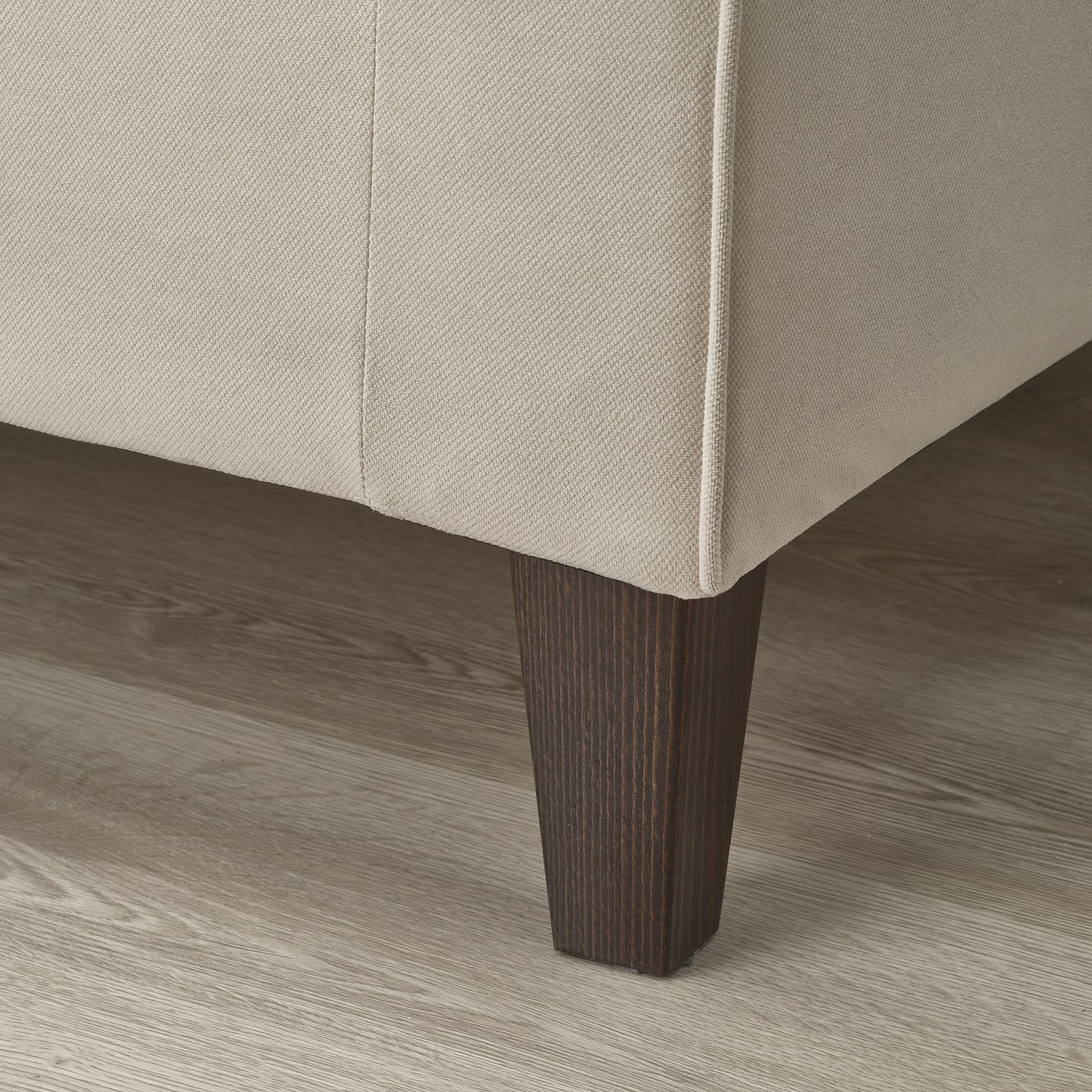Close-up of modern sofa leg: sleek wood finish, sturdy design, part of stylish EKHOLMA collection.