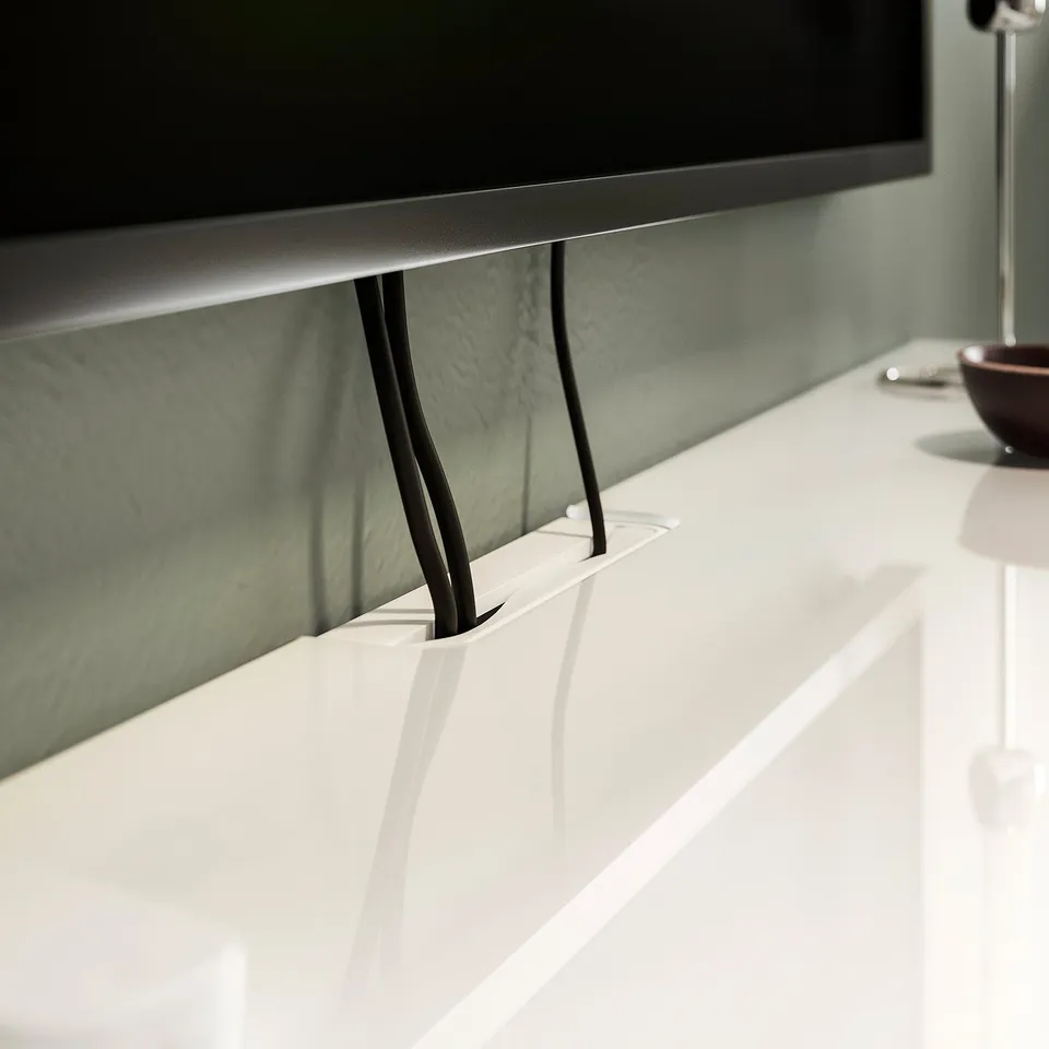White glass top panel on desk, supporting tv stand with cable management.