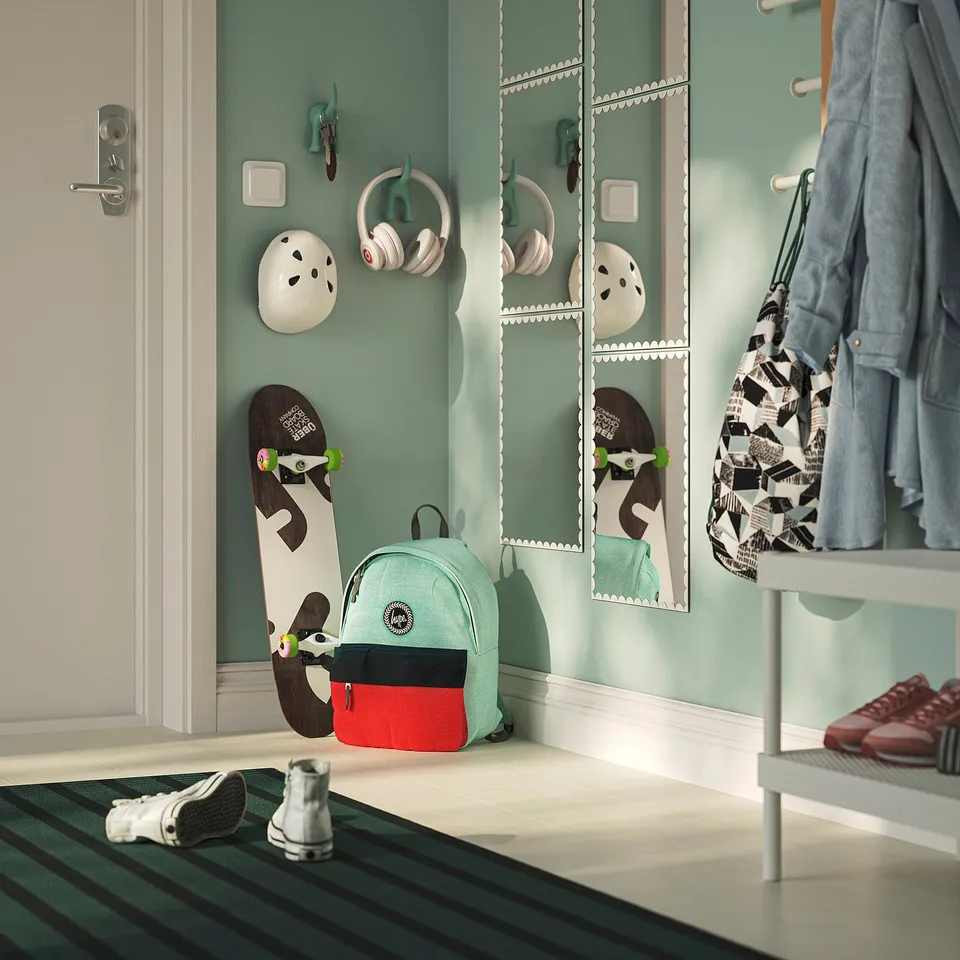 A hallway green walls with RUNDOXEL decorative mirrors, a white helmet, headphones, a skateboard, and a backpack.