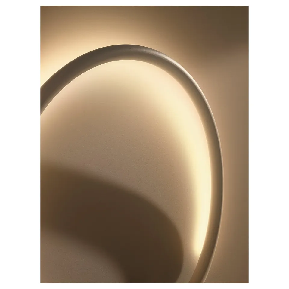 Circular led wall lamp with warm glow, gold hue, sleek design.