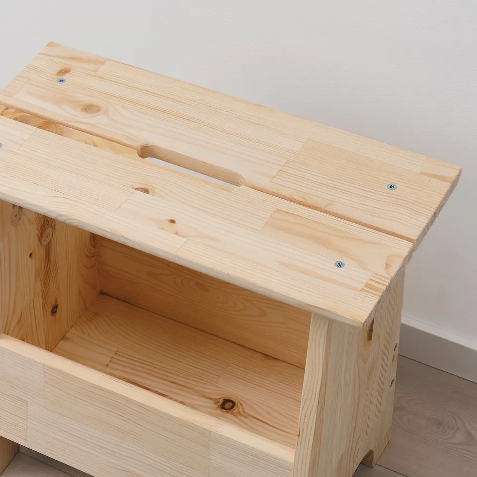 Natural wood stool with storage, featuring cut-out handle, shown in minimalist room.
