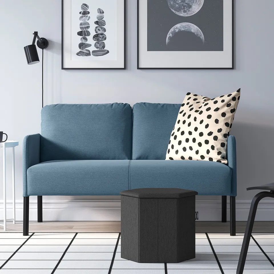 Modern blue sofa with polka dot pillow, sleek side table, grey walls, artwork, and floor lamp. Perfectly sized for cosy living spaces.