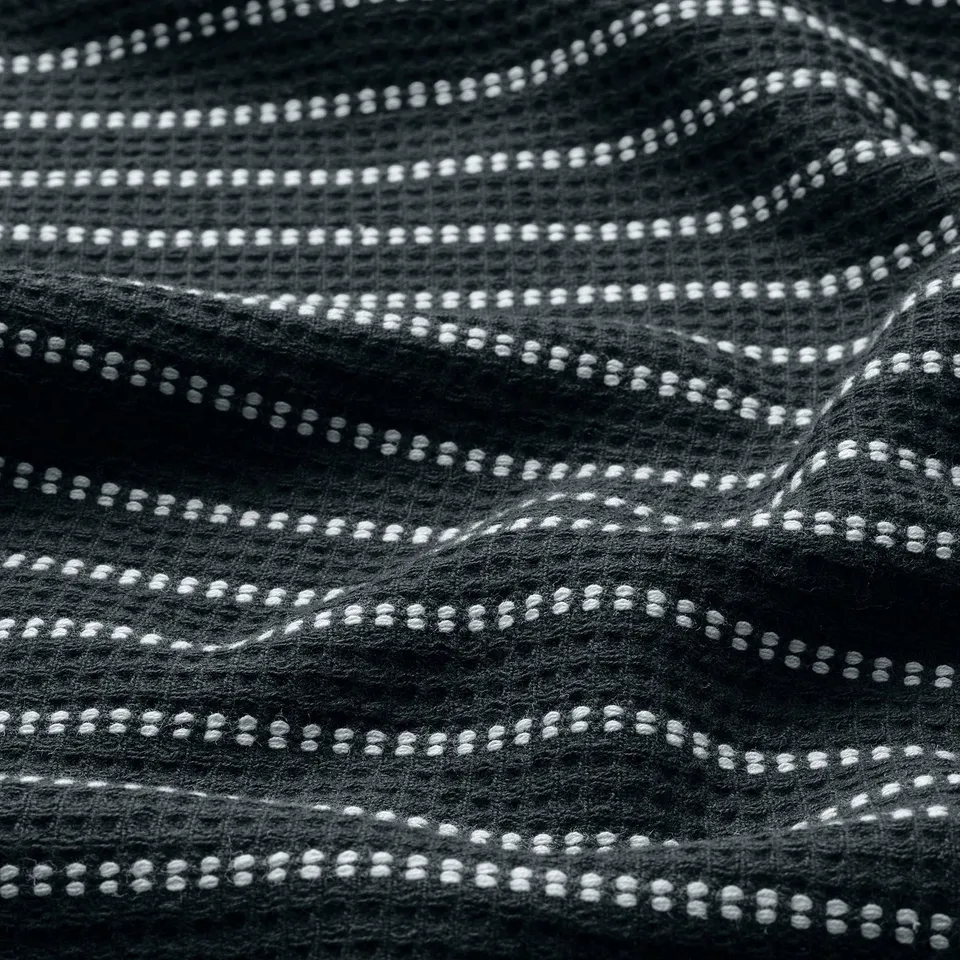 Black and white close-up of a waffle-weave towel. Visible detailed texture, showing the intricate pattern.