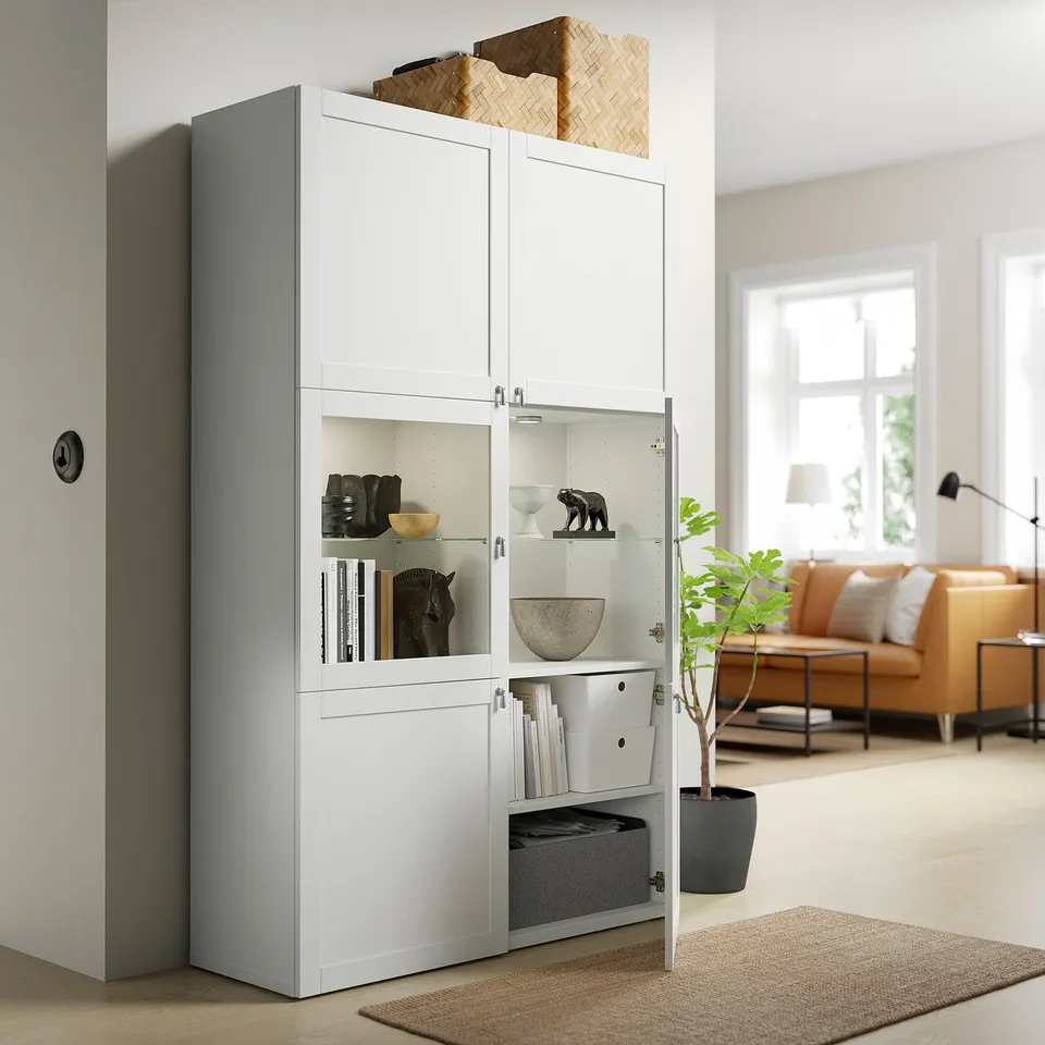 BESTÅ glass door unit with decorative items and open door showing books.