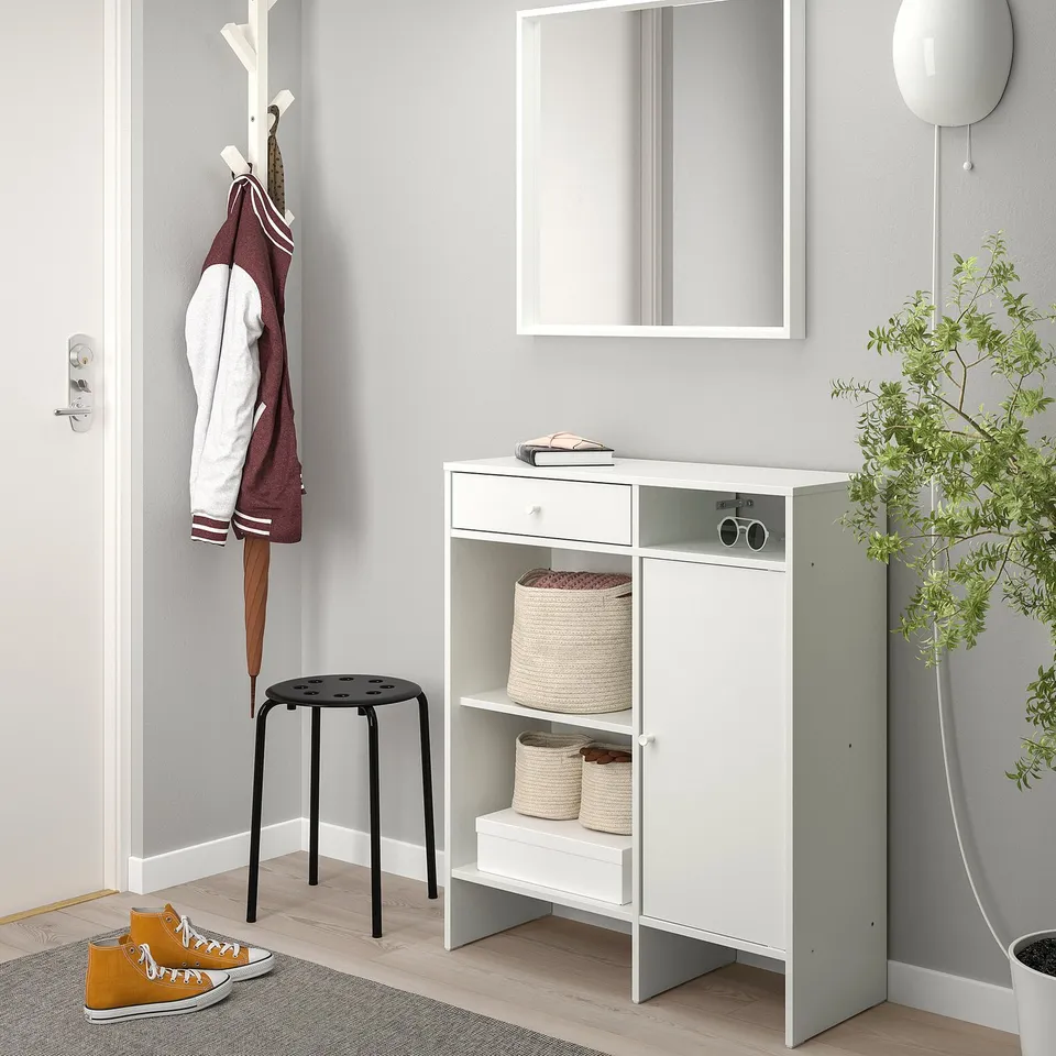 White sideboard with open & closed storage, baskets, mirror, coat hooks, black stool, yellow trainers.