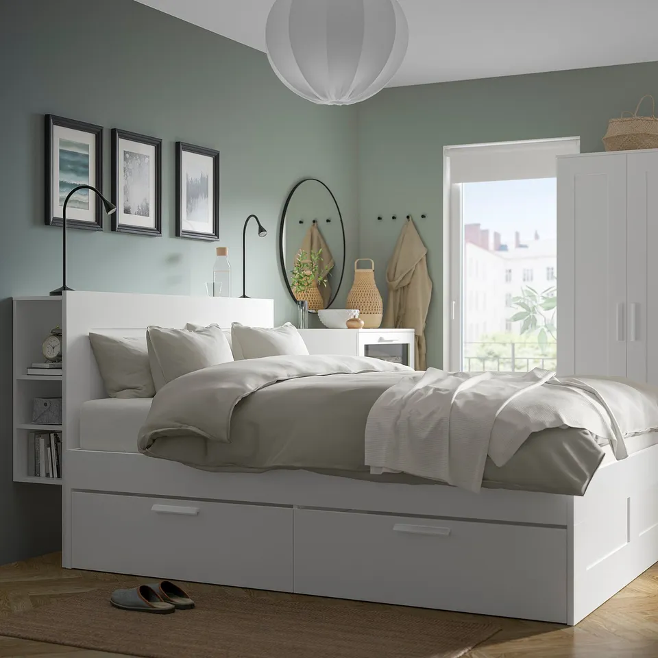Cosy bedroom with teal walls, a white bed with grey linens, and wall-mounted NÄVLINGE lamp offering focused light.